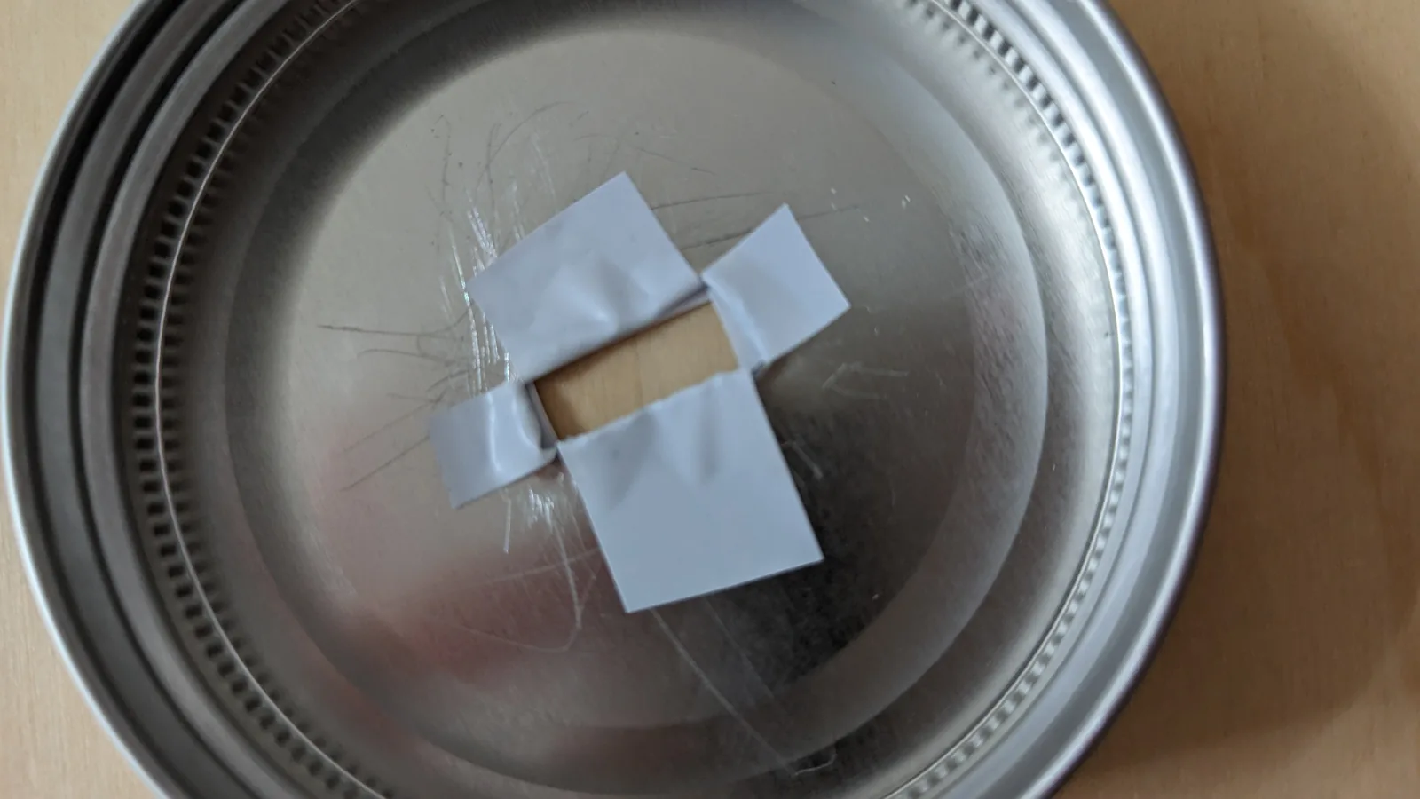 ヤスリをかけた瓶の蓋の穴の切り口をビニールテープで覆う