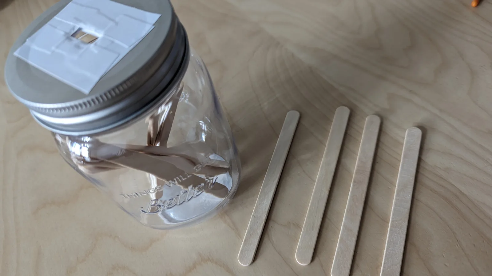 完成した穴あきプラスチック製瓶に木製スティックを入れる