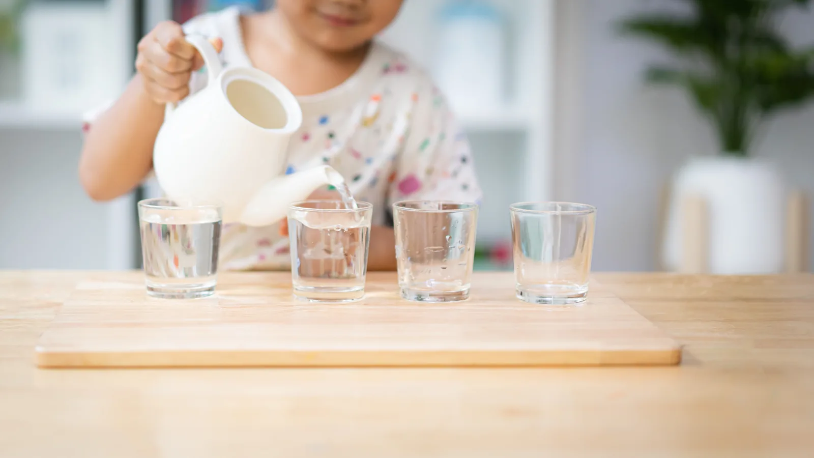 ピッチャーでコップに水を注ぐ子ども。